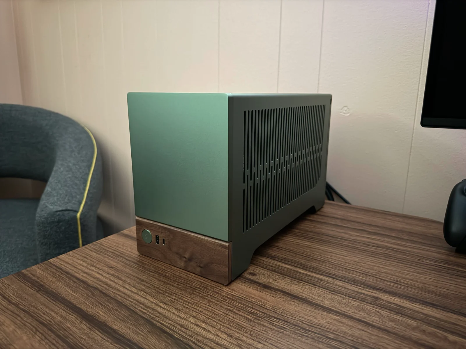 The completed PC in a jade green Fractal Terra case with a walnut front panel, sitting on a wooden desk.